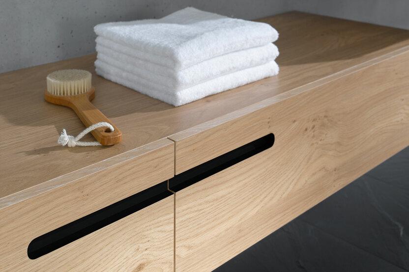 Detailaufnahme eines Waschtischunterschrankes aus Massivholz Detailaufnahme eines schmalen Waschtischunterschrankes aus Massivholz mit eingelassenen Griffen